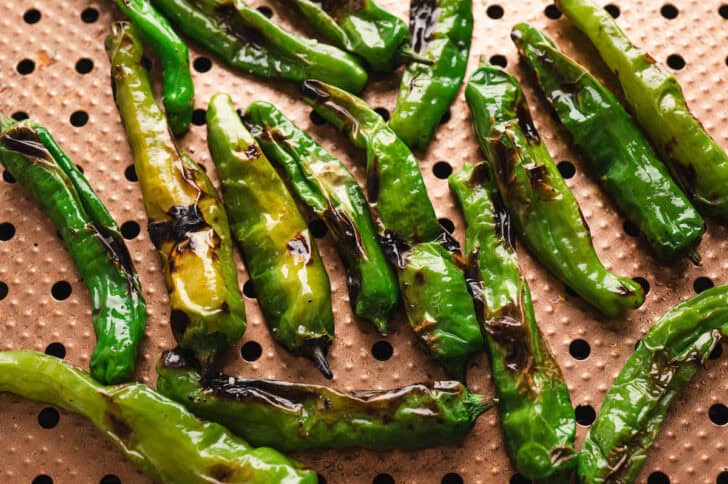 Shishito peppers in a grill basket.