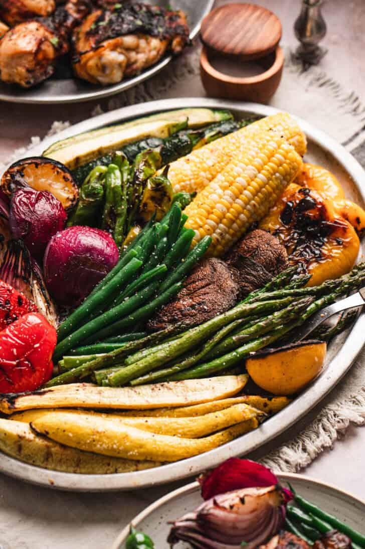 A platter of the best vegetables to grill, including beans, asparagus, corn, bell peppers, squash, mushrooms, corn and onion.