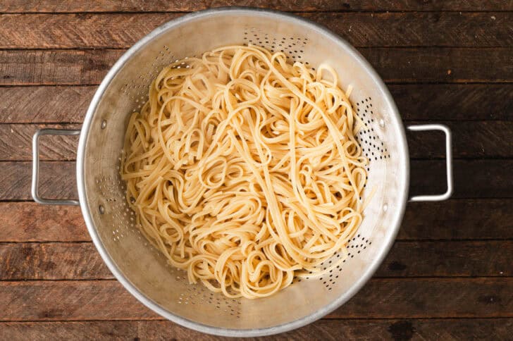 A colander filled with cooked linguine.