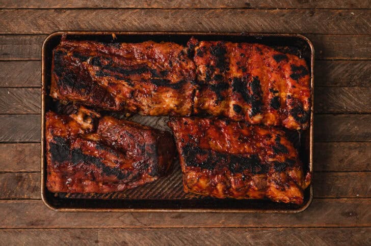 Slabs of grilled meat on a rimmed baking pan.