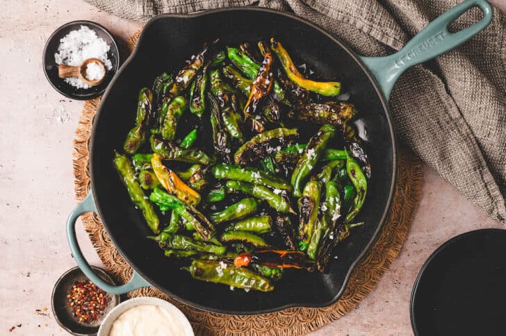 A cast iron skillet filled with blistered green vegetables.