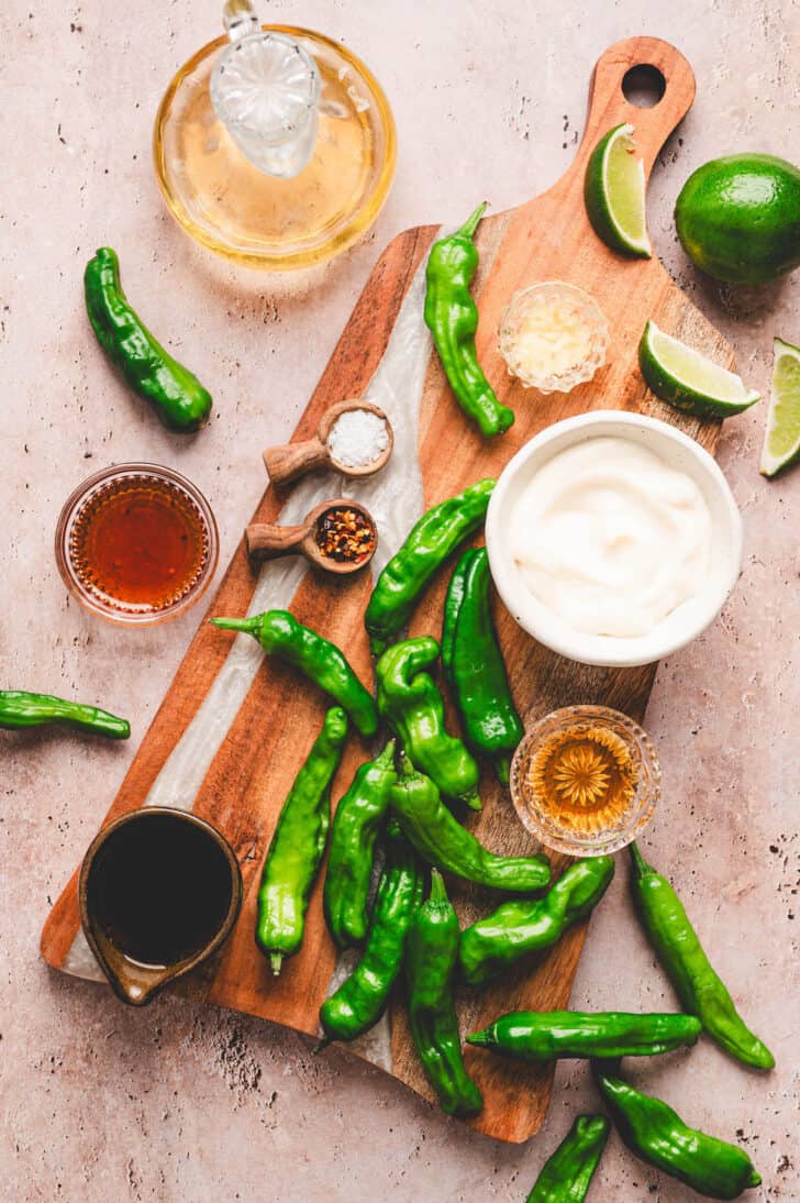 Ingredients for a shishitos pepper recipe, including the peppers, limes and condiments.