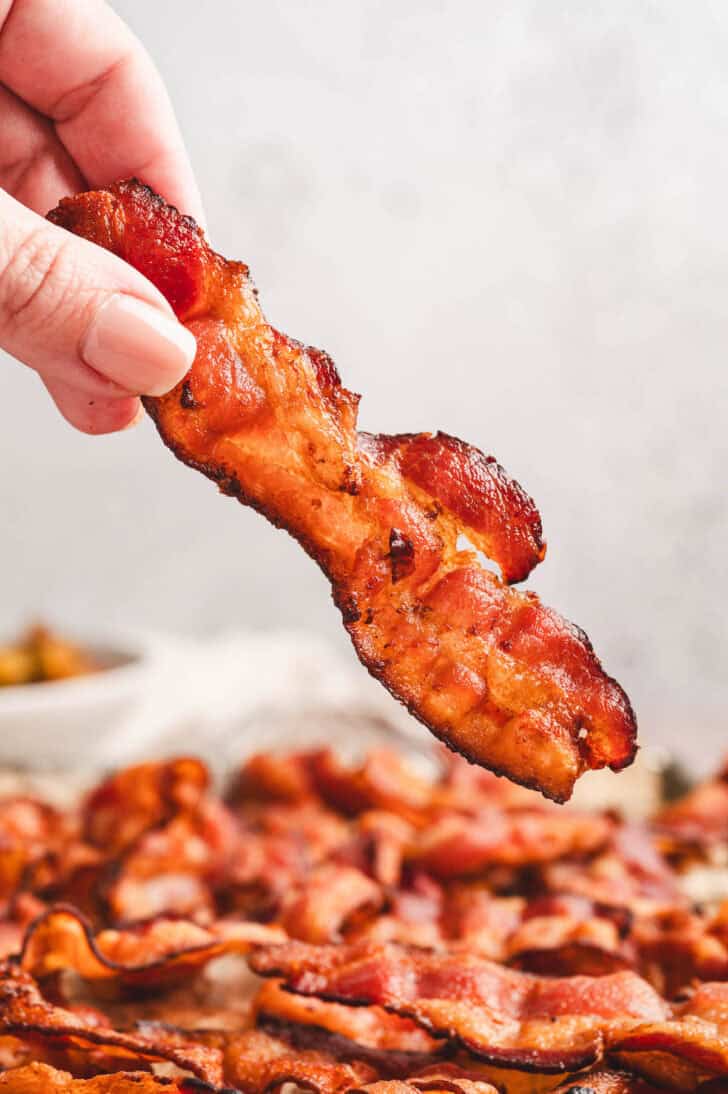 A hand picking up a piece of crispy pork belly.