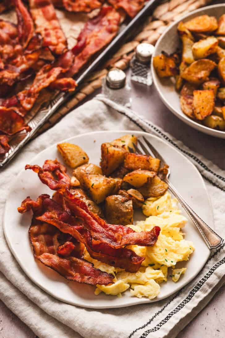 A plate with scrambled eggs, bacon and potatoes.