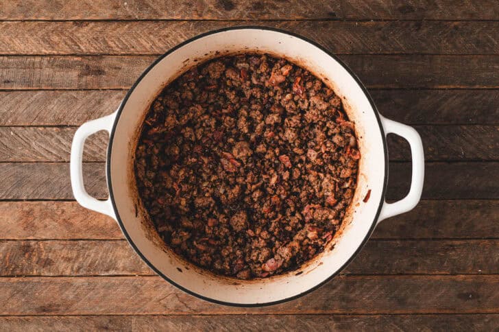 A white Dutch oven filled with cooked ground beef.