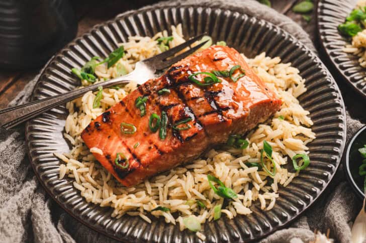 A plate with rice topped with a recipe for grilled salmon.