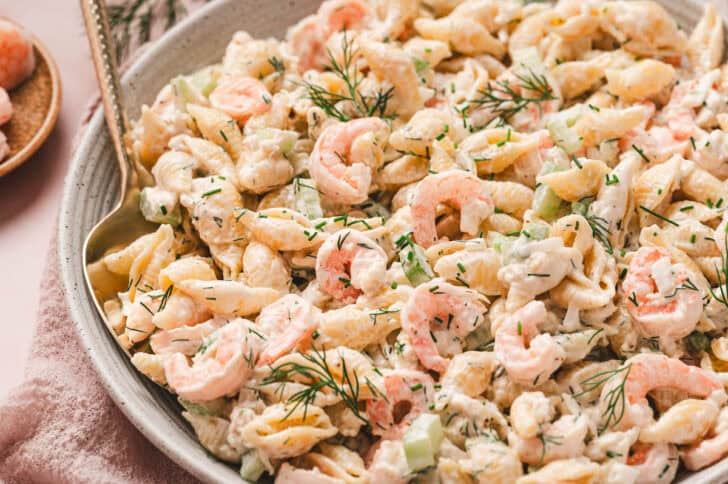 A bowl of shrimp crabmeat pasta salad with a spoon in it.