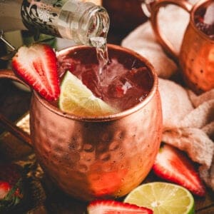 A strawberry mule being topped off with ginger beer.