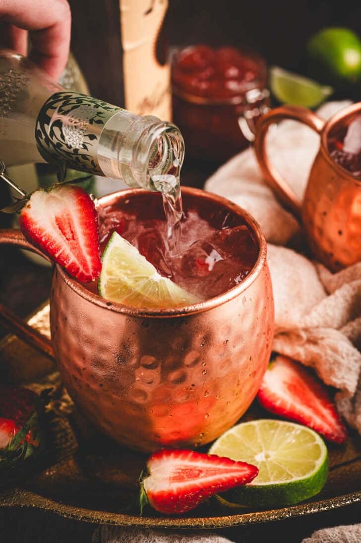 A strawberry mule being topped off with ginger beer.
