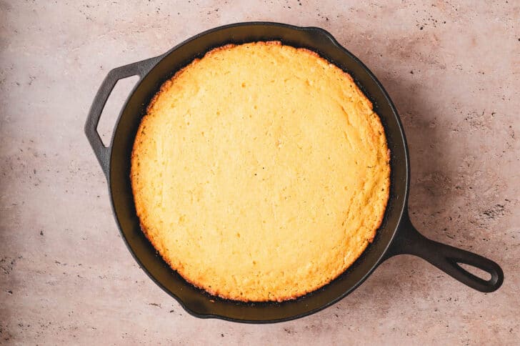 A cast iron skillet filled with a honey cornbread recipe.