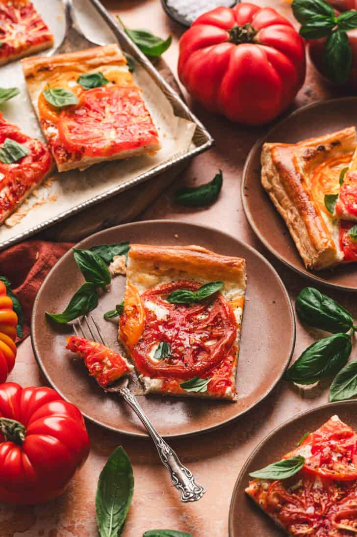 A siice of puff pastry tomato tart on a small plate.