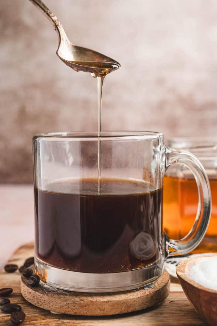 Caramel coffee syrup being drizzled into a mug of coffee.