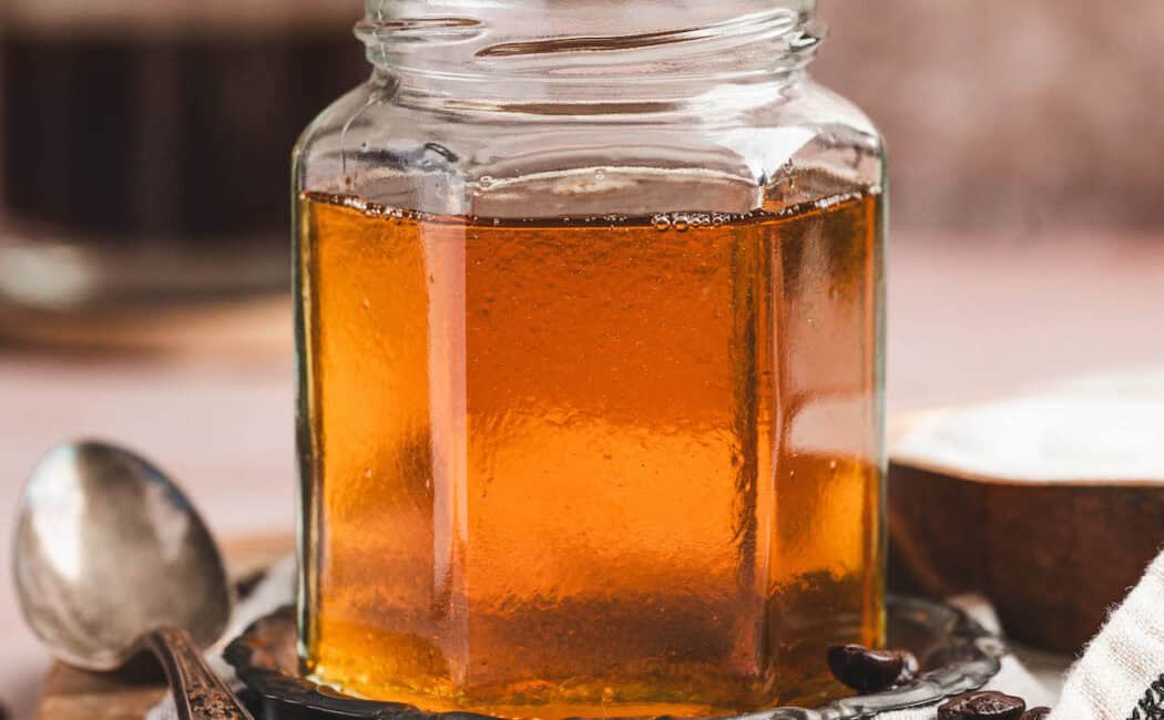 A glass jar of caramel syrup for coffee.