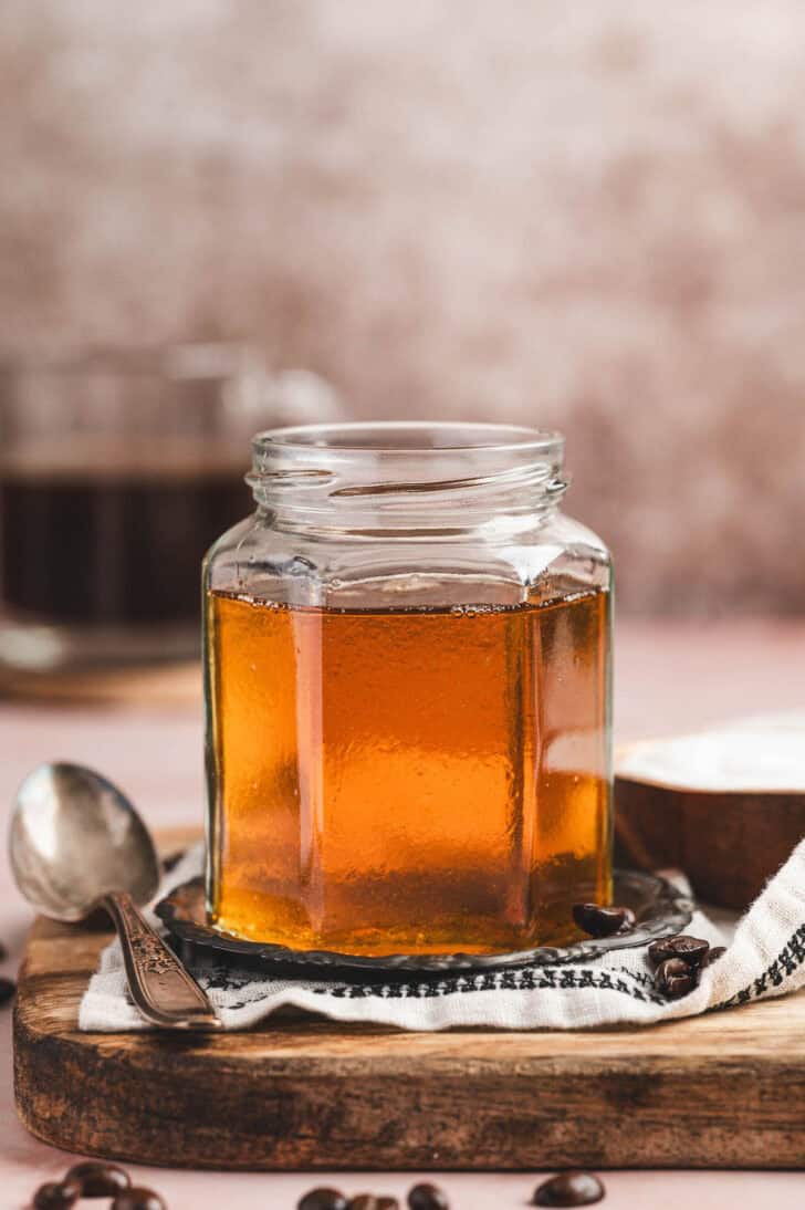 A glass jar of caramel syrup for coffee.