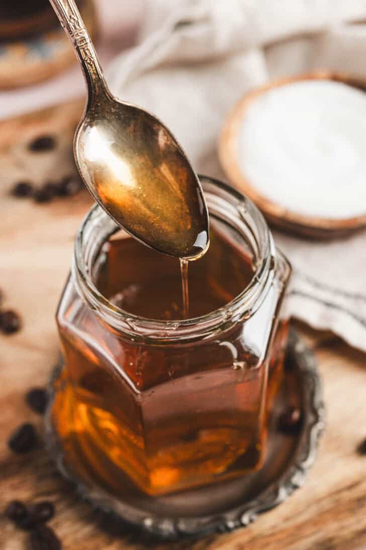 Homemade caramel coffee syrup being drizzled into a jar.