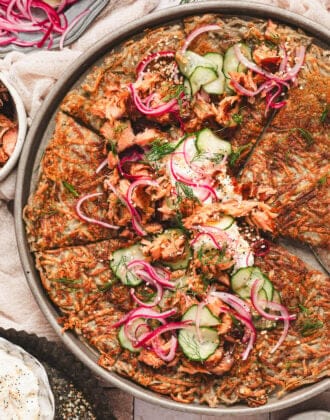 A potato rosti topped with cream cheese, smoked salmon, cucumbers and red onions.