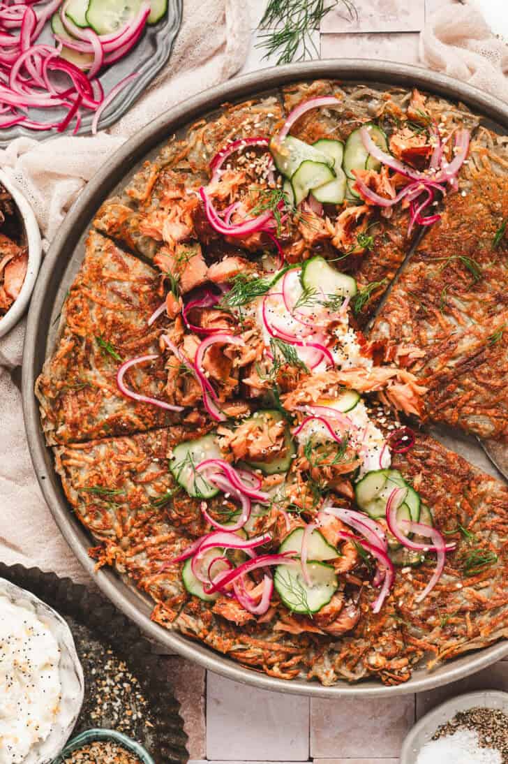 A potato rosti topped with cream cheese, smoked salmon, cucumbers and red onions.