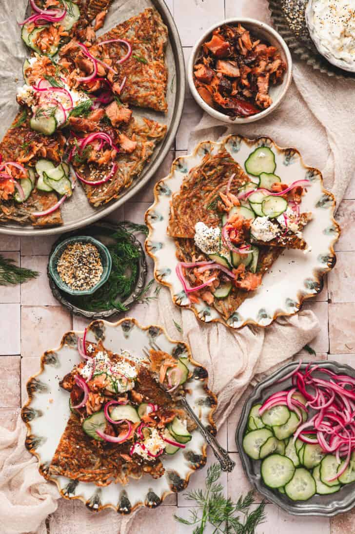 Two plates with potato rosti and lots of garnishes.