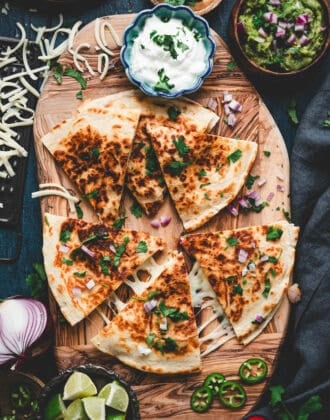 A shrimp quesadilla recipe on a wooden cutting board, surrounded by condiments.