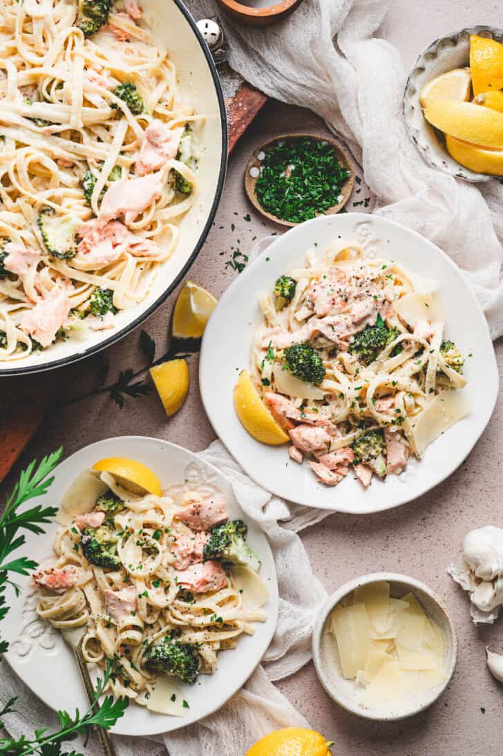 A salmon alfredo recipe plated in fancy white dishes.