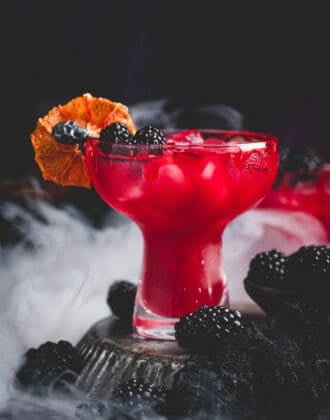 A deep red Halloween margarita garnished with blackberries and a bloody rim.
