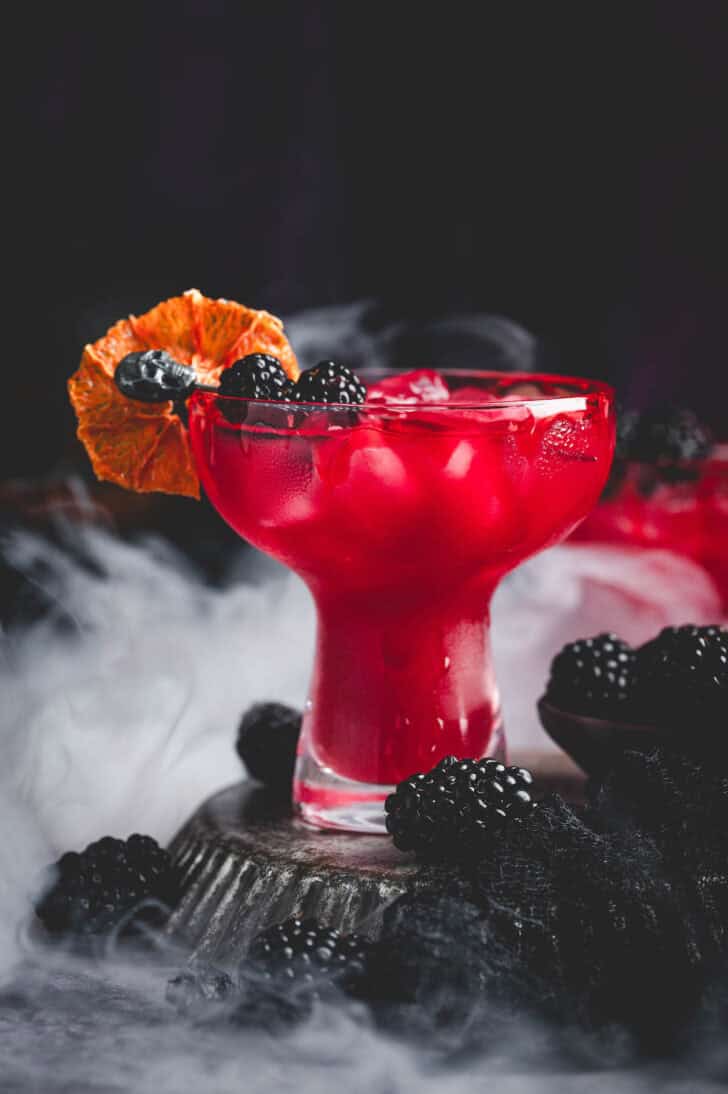 A deep red Halloween margarita garnished with blackberries and a bloody rim.