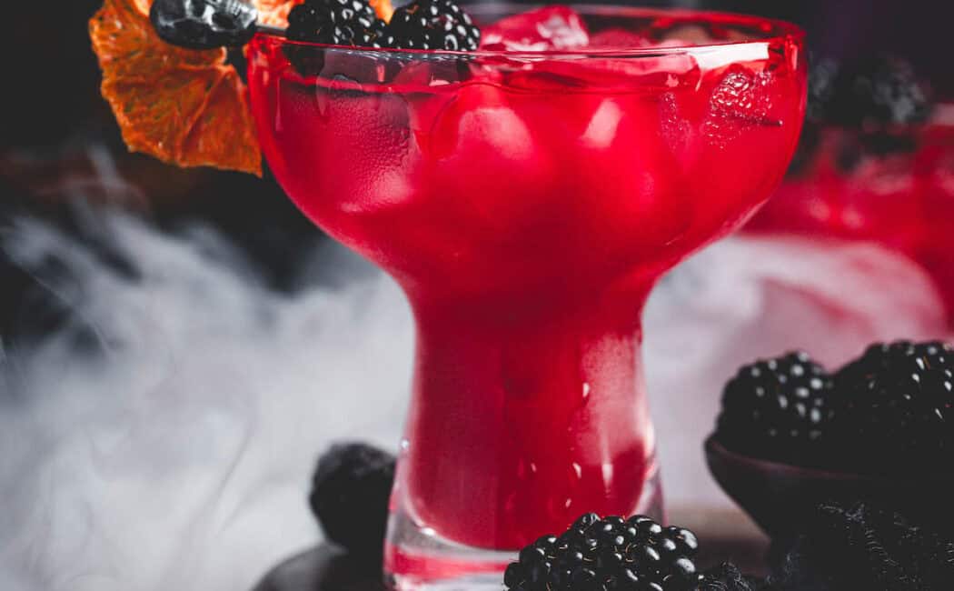 A deep red Halloween margarita garnished with blackberries and a bloody rim.