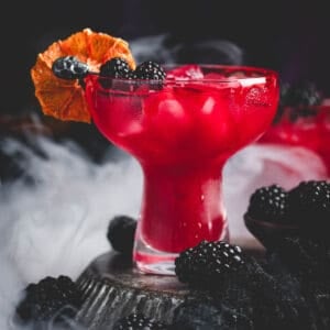 A deep red Halloween margarita garnished with blackberries and a bloody rim.