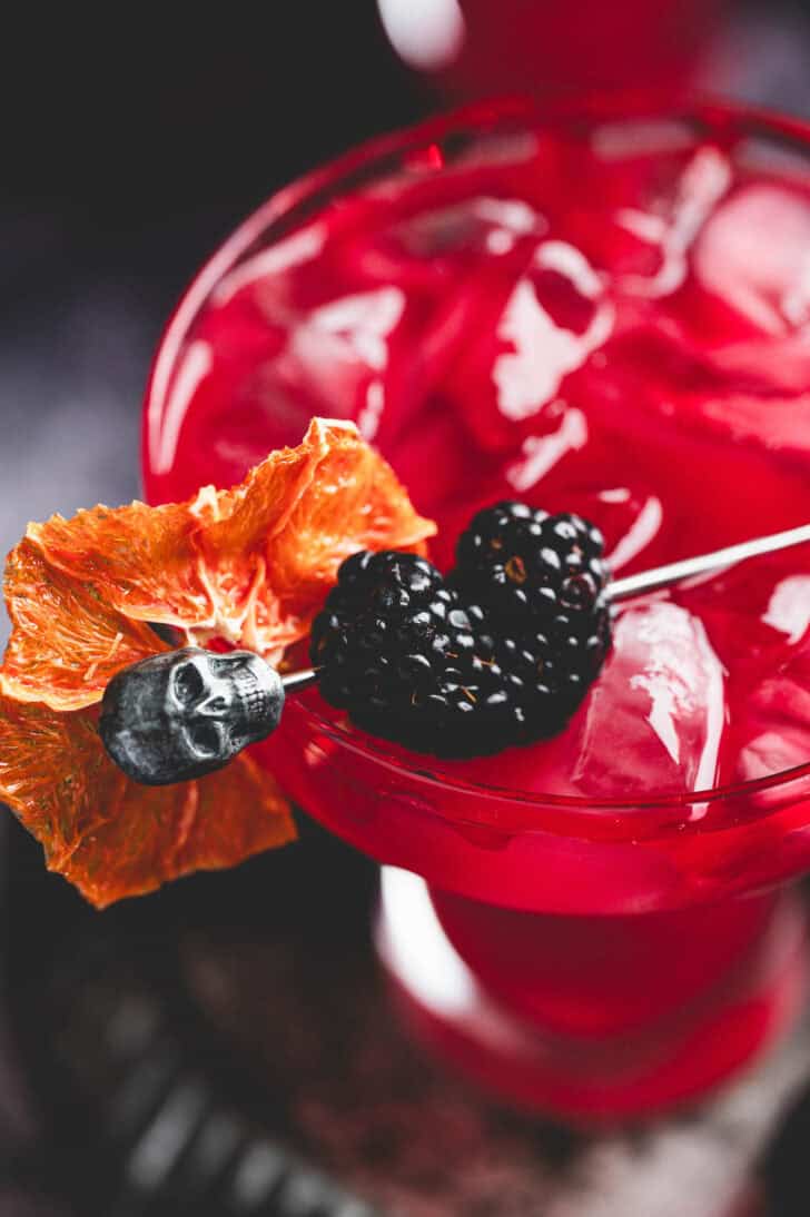 A deep red Halloween margarita garnished with blackberries and a bloody rim.