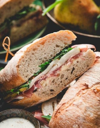 A halved prosciutto sandwich showing layers of colorful ingredients.
