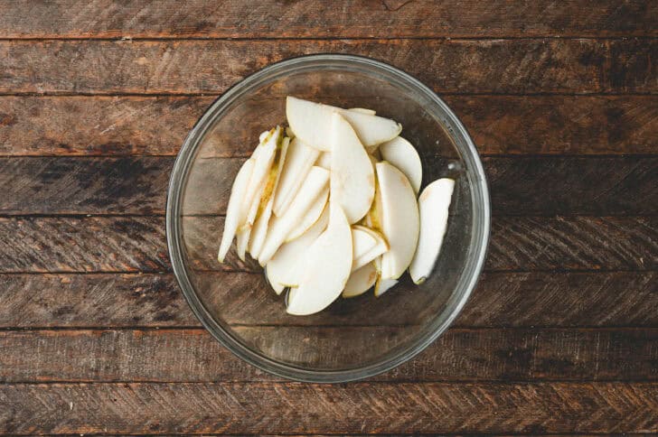 A glass bowl filled with sliced pears.