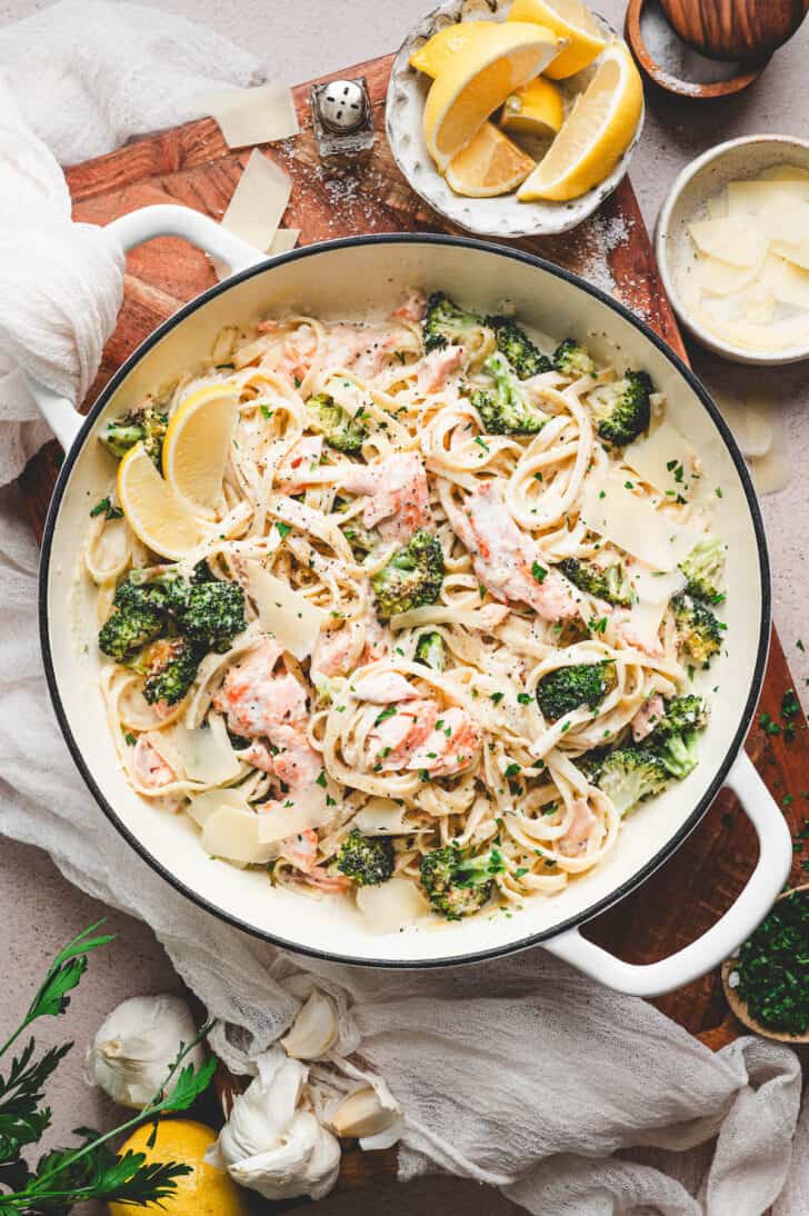 A white dutch oven filled with salmon alfredo.