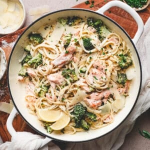 A white dutch oven filled with salmon alfredo.