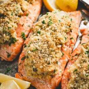Pieces of stuffed salmon on a platter with lemon wedges.