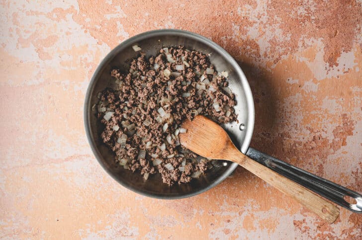 A skillet filled with ground beef and onion.