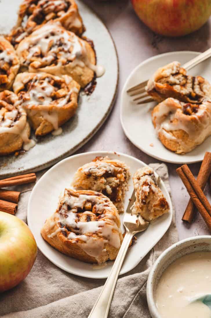 Cinnamon apple rolls, on small plates, with a fork scooping a bite.