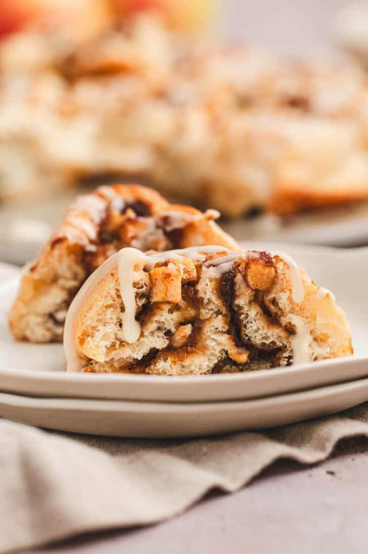 A cinnamon roll with apples, cut in half so you can see the inside, on a plate.