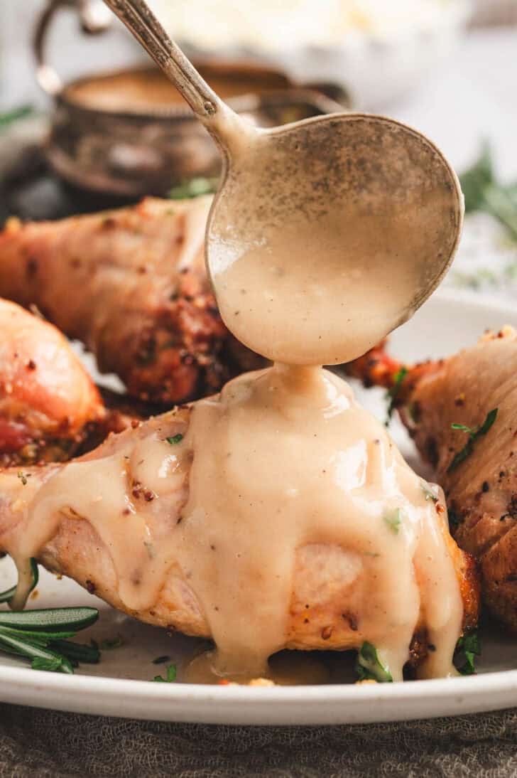 A ladle drizzling an easy gravy recipe over turkey legs.