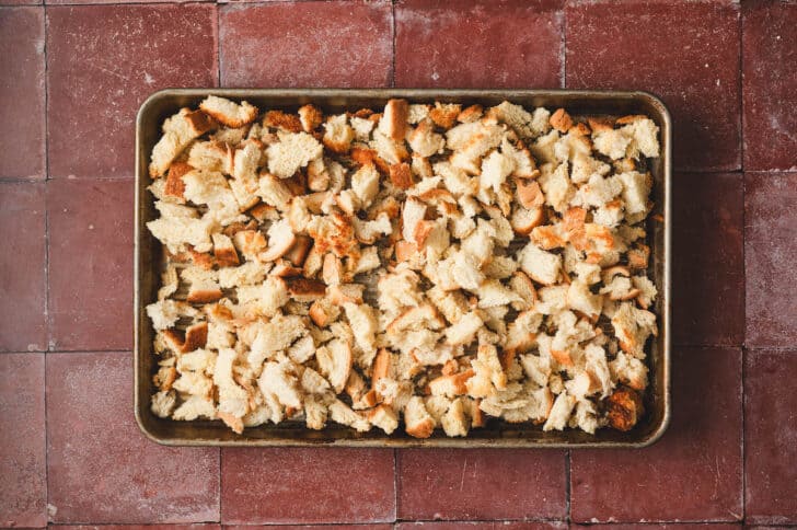 Cubes of toasted bread on a rimmed baking pan.