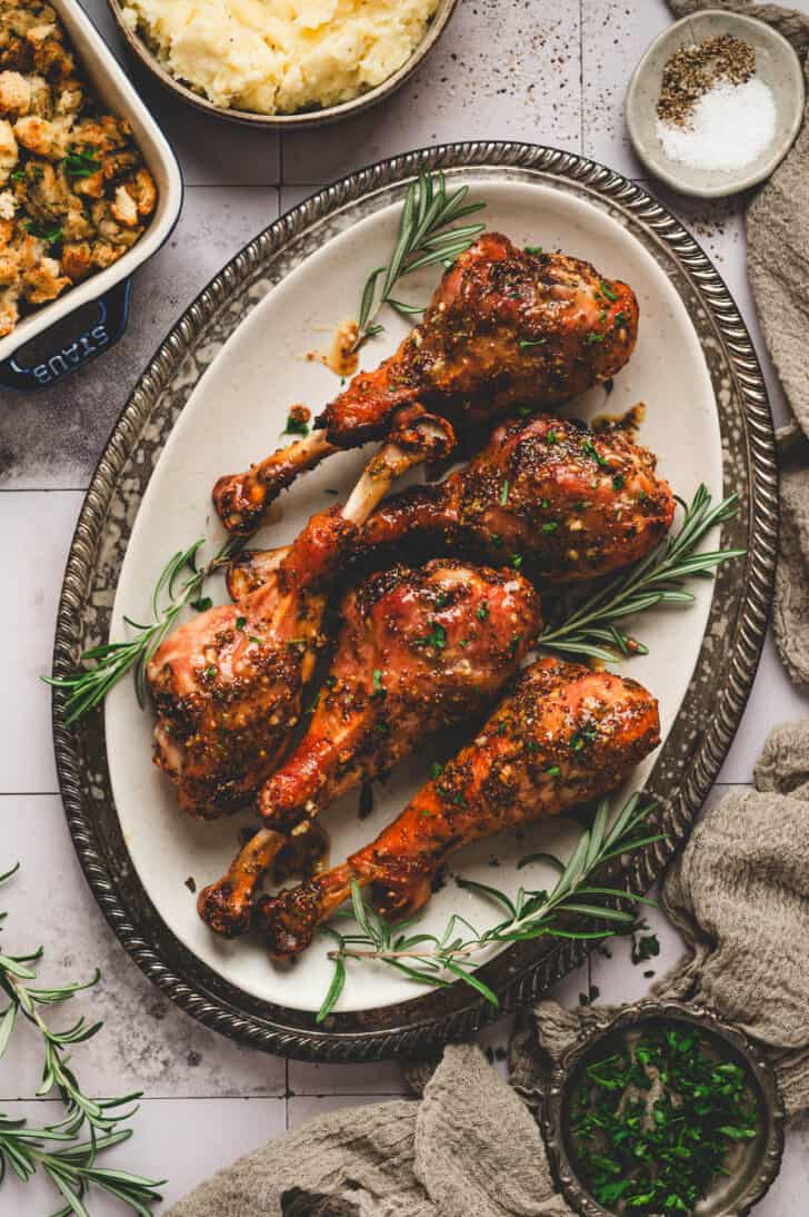 A large platter filled with five roasted turkey legs.