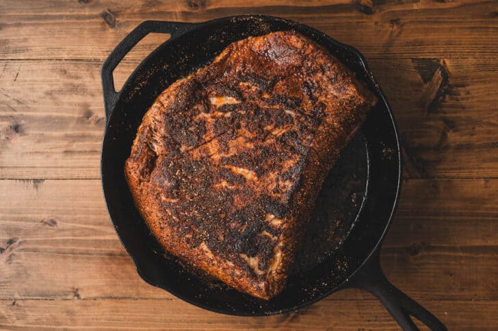 A large piece of meat in a cast iron skillet.