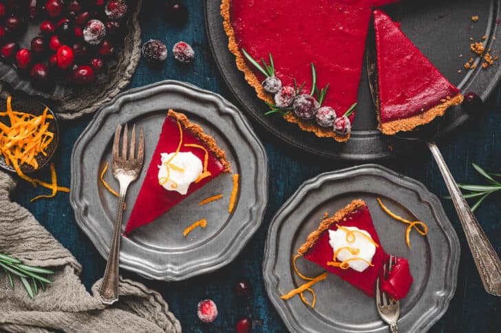 Two slices of cranberry tart on silver plates.