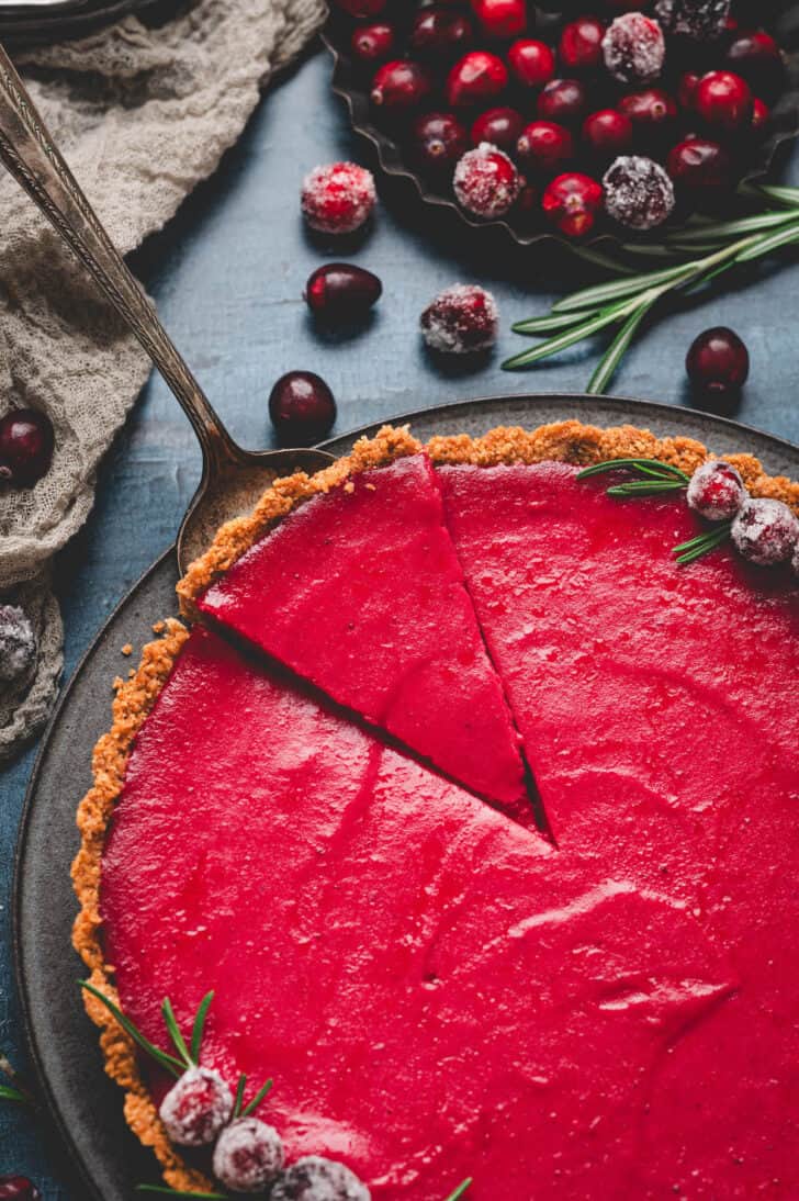 A server lifting a slice of a cranberry curd tart recipe.