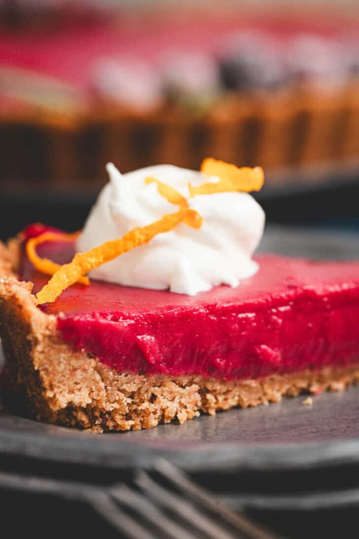 A slice of cranberry curd pie topped with whipped cream.