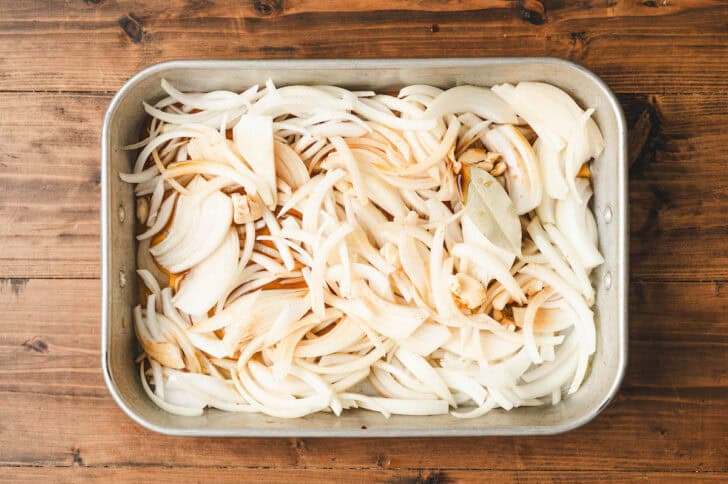 A roasting pan full of sliced onions.