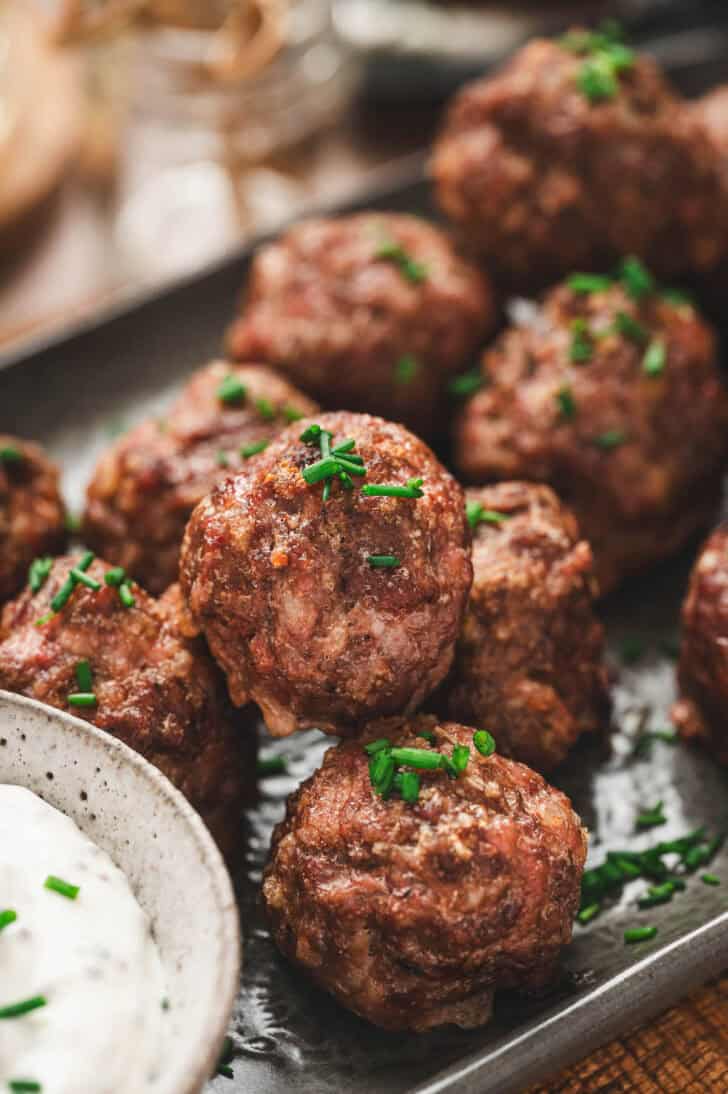 A closeup photo of cocktail meatballs sprinkled with chives.