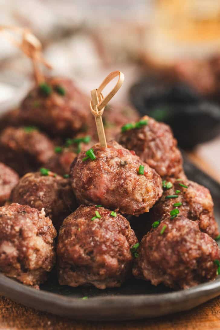 A pile of savory cocktail meatballs with toothpicks in some.