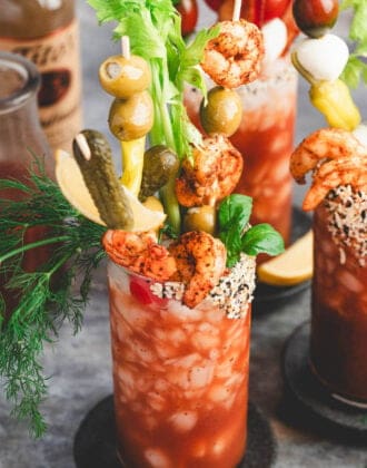 A bloody mary with lots of bloody mary garnish skewers in it.