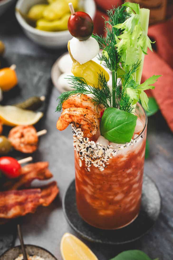 A red drink with lots of bloody mary garnishes in it.