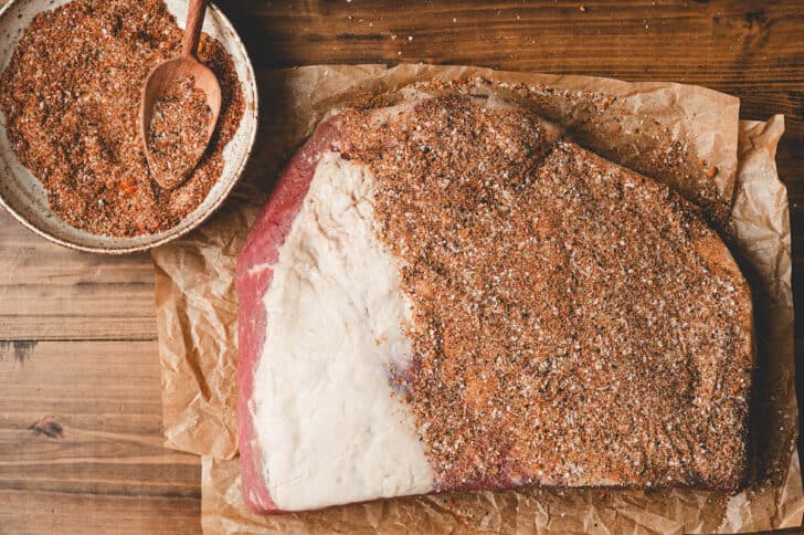 A brisket being rubbed with dry rub for brisket.